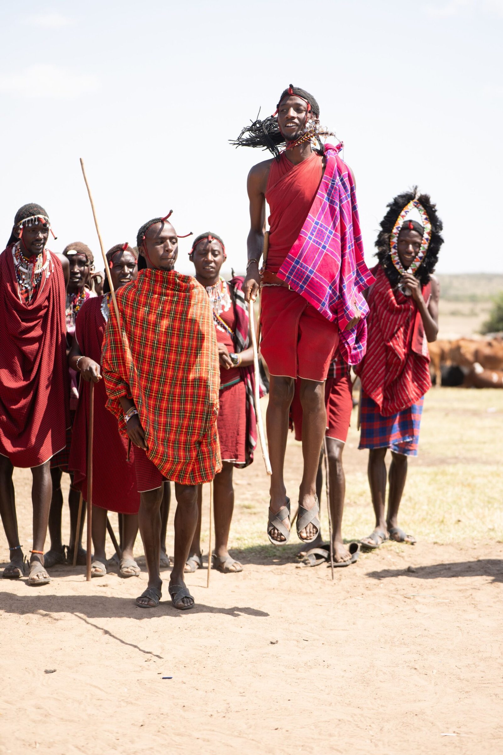 Maasai tribe members performing a traditional jumping dance in Kenya's open landscape.